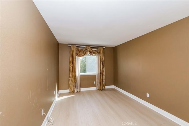 unfurnished room with light wood-type flooring and baseboards