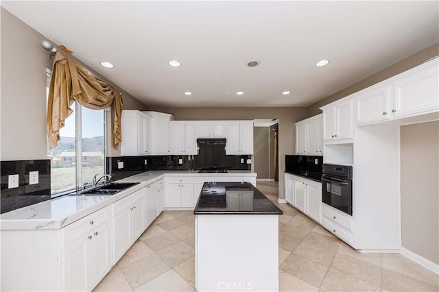 kitchen with a sink, white cabinetry, a center island, black appliances, and tasteful backsplash