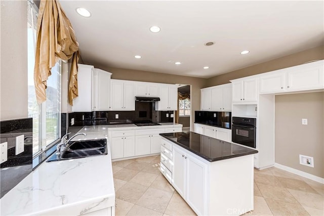 kitchen featuring white cabinets, oven, a center island, gas cooktop, and a sink