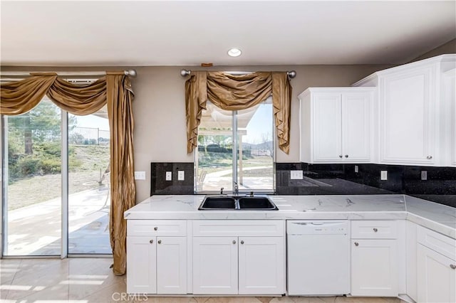 kitchen featuring light stone countertops, a sink, white cabinets, decorative backsplash, and dishwasher