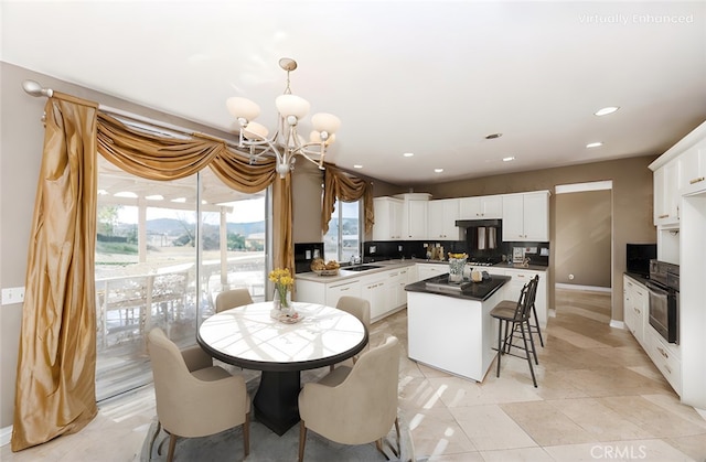 kitchen featuring dark countertops, an inviting chandelier, white cabinets, a sink, and oven