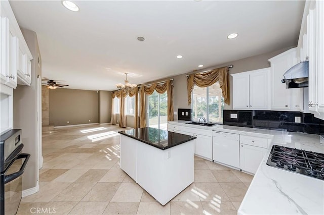 kitchen featuring dark stone counters, white cabinets, dishwasher, a kitchen island, and under cabinet range hood