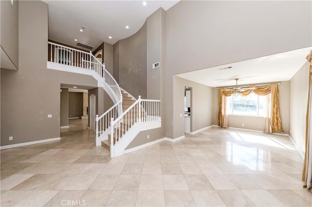 interior space featuring a towering ceiling, visible vents, stairway, and baseboards