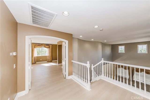 hall with arched walkways, recessed lighting, an upstairs landing, light wood-style floors, and visible vents