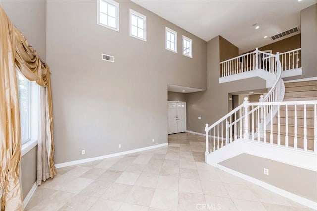 unfurnished living room featuring stairway, visible vents, light tile patterned floors, and baseboards