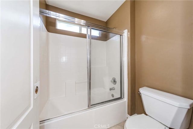 bathroom featuring toilet and bath / shower combo with glass door