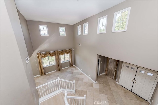 foyer featuring a towering ceiling, visible vents, and baseboards