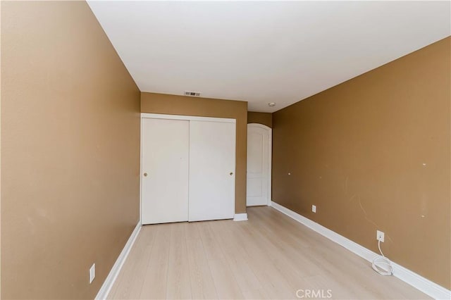 unfurnished bedroom featuring light wood-style floors, a closet, visible vents, and baseboards