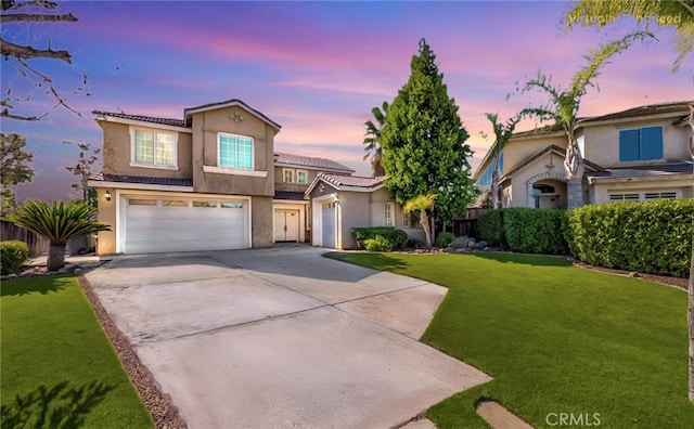 view of front of property with stucco siding, a lawn, an attached garage, driveway, and a tiled roof