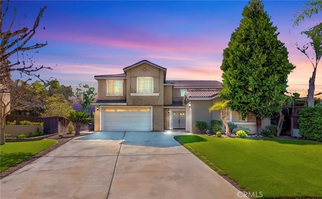 view of front of home featuring stucco siding, an attached garage, fence, driveway, and a front lawn