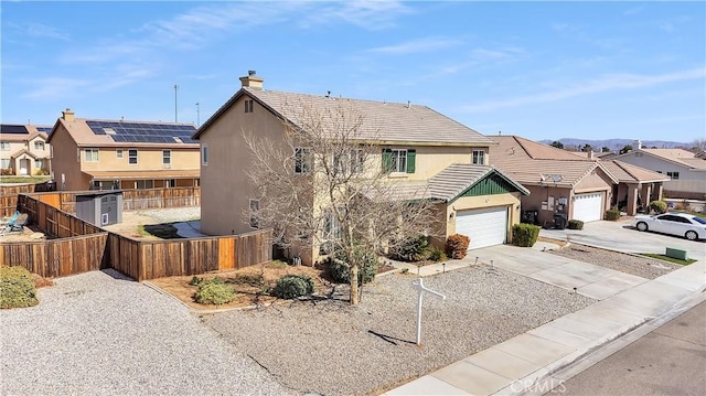 view of front of home with stucco siding, concrete driveway, an attached garage, fence, and a residential view