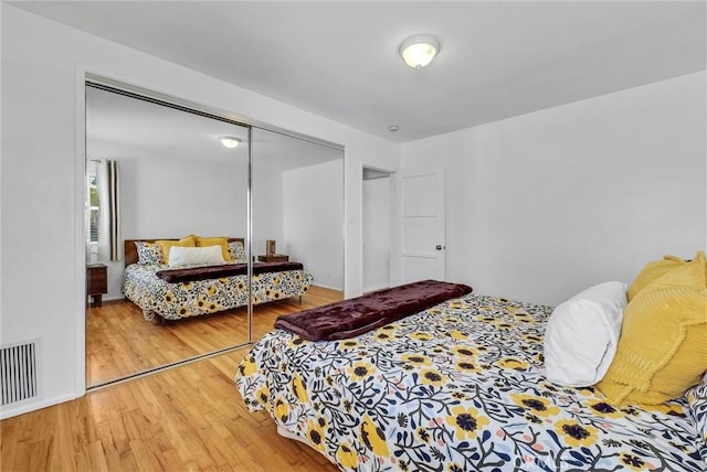 bedroom with a closet, visible vents, and wood finished floors