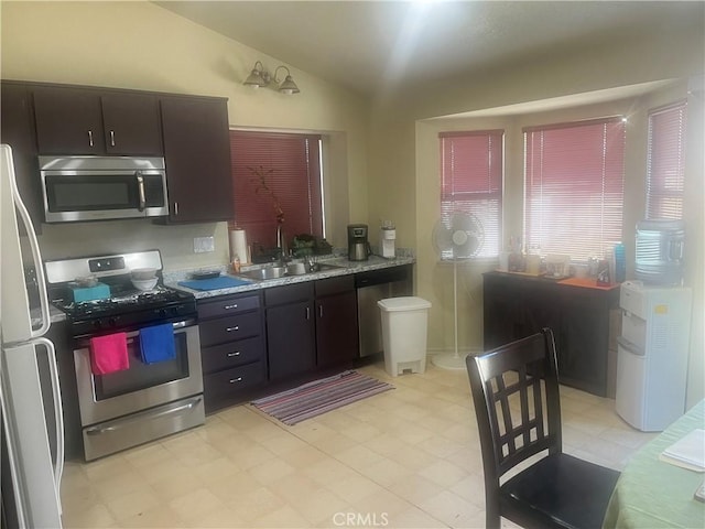 kitchen featuring a sink, appliances with stainless steel finishes, vaulted ceiling, and dark brown cabinets