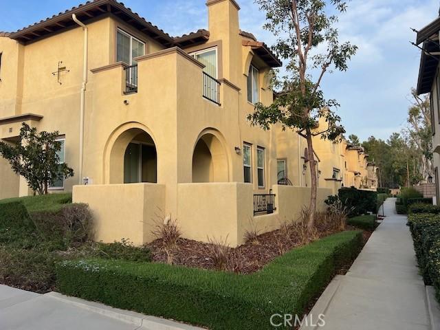 view of property exterior featuring a fenced front yard, a chimney, stucco siding, a balcony, and a tiled roof