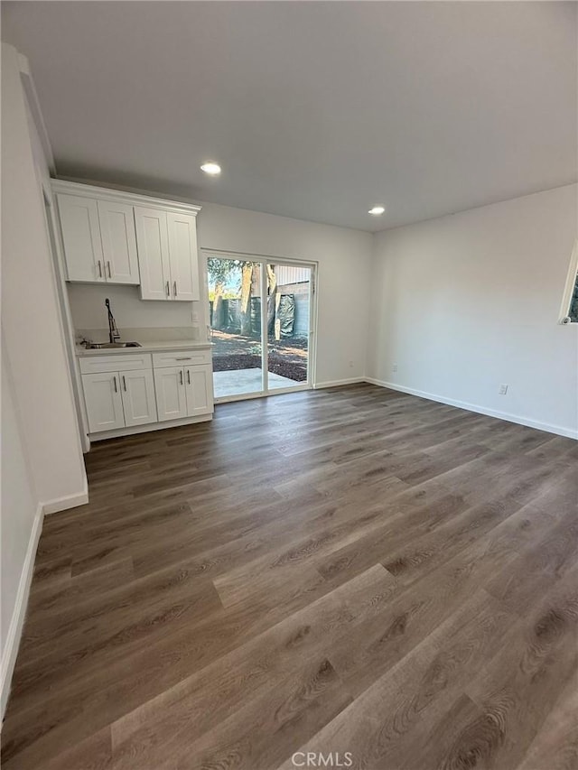 interior space featuring baseboards, dark wood-type flooring, a sink, and recessed lighting