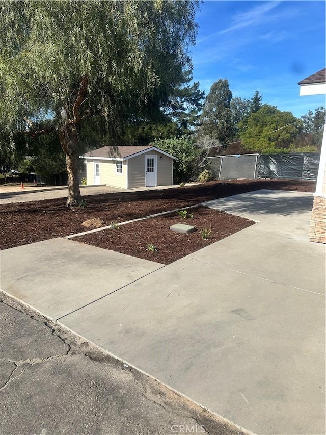 view of yard with driveway, fence, and an outdoor structure