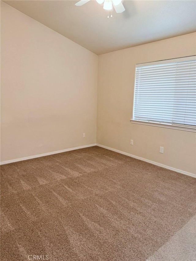 carpeted spare room featuring baseboards and a ceiling fan