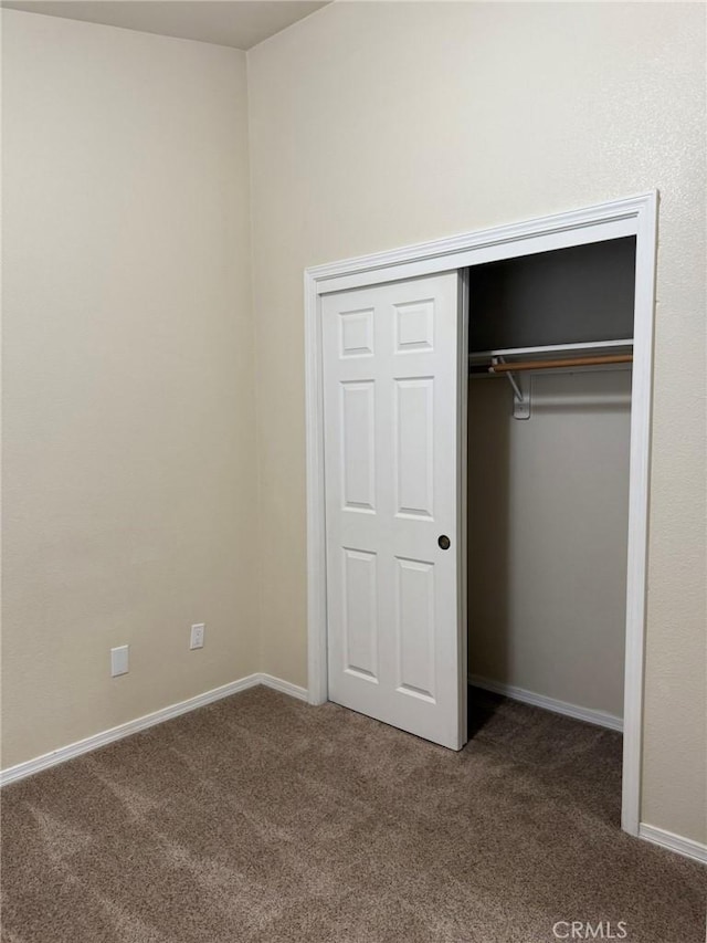 unfurnished bedroom with carpet, baseboards, and a closet