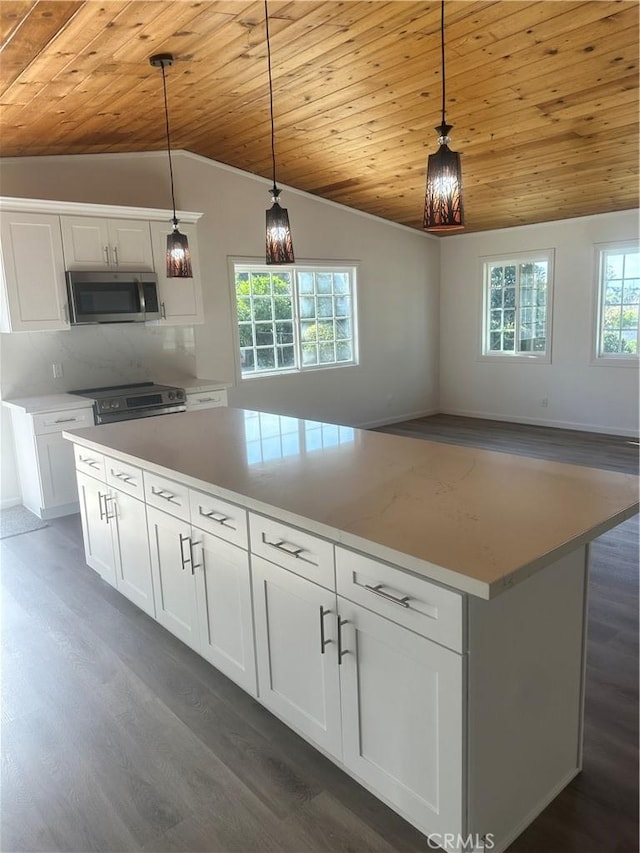 kitchen with open floor plan, stainless steel appliances, hanging light fixtures, and white cabinetry