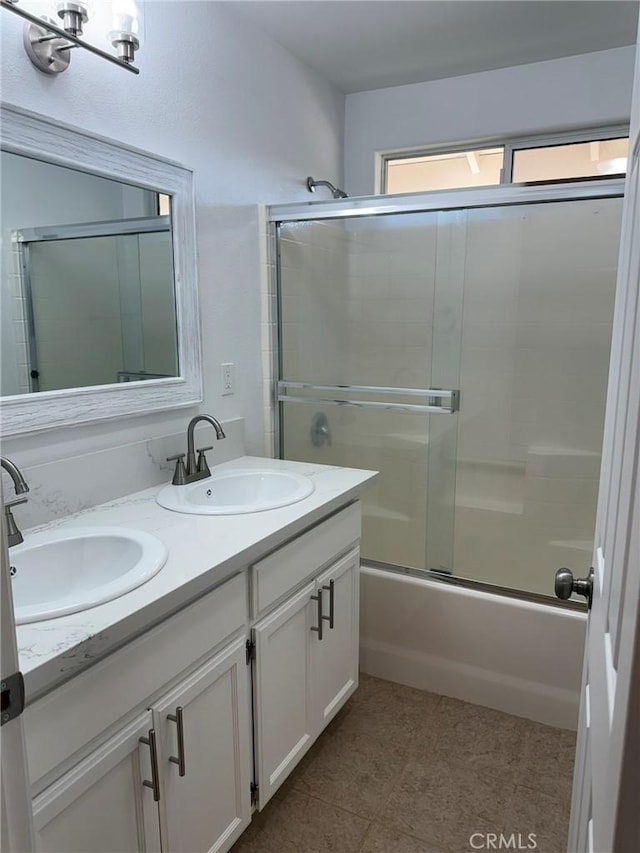 bathroom with combined bath / shower with glass door, a sink, and double vanity