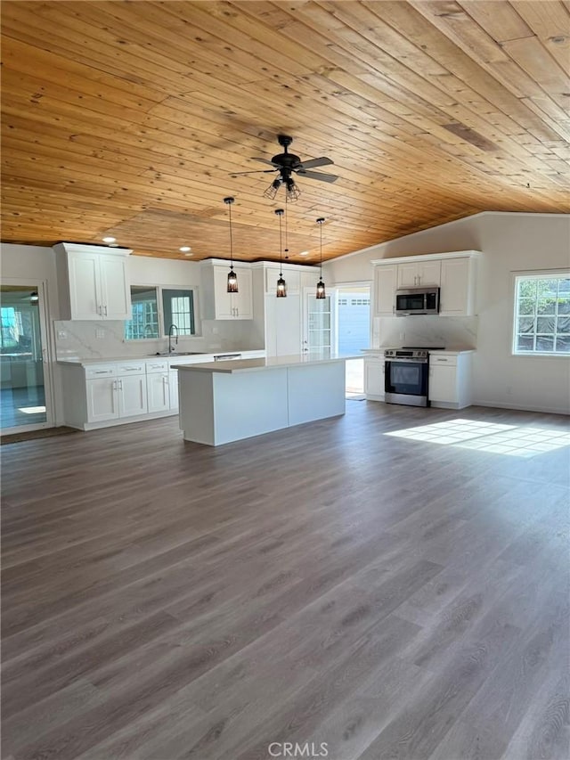 kitchen with stainless steel appliances, hanging light fixtures, light countertops, and white cabinetry