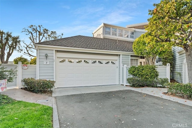 view of front of property with driveway, an attached garage, and fence