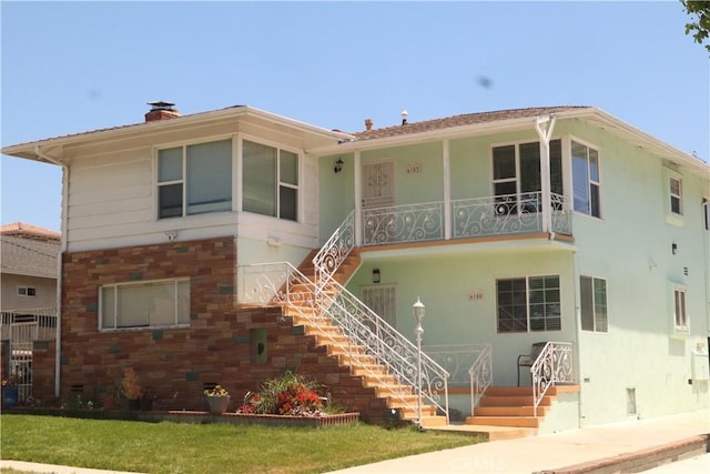 view of front of house featuring stucco siding, a chimney, and stairs