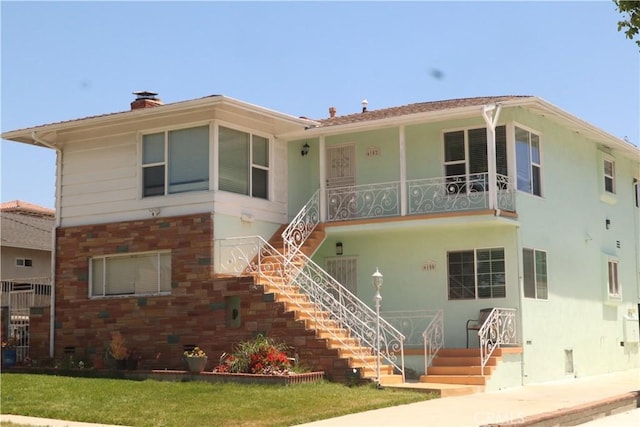 view of front facade with covered porch, a chimney, stairs, and stucco siding