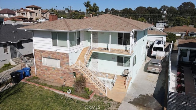 view of front of property with a shingled roof, a chimney, a residential view, and stucco siding