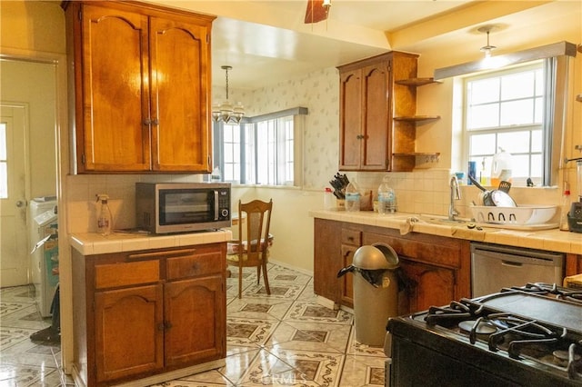 kitchen with a sink, stainless steel microwave, tile countertops, and brown cabinets