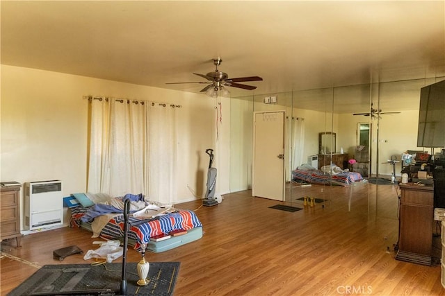 living room featuring heating unit, ceiling fan, and wood finished floors