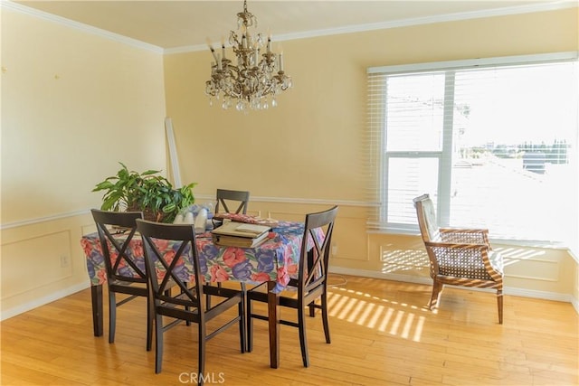 dining room featuring light wood-style floors, crown molding, a notable chandelier, and a healthy amount of sunlight