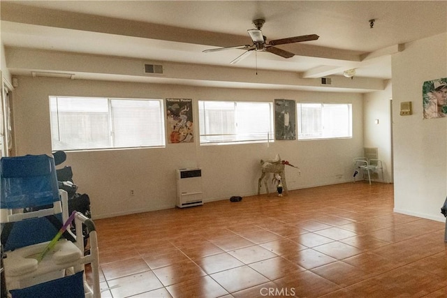 tiled spare room with ceiling fan, visible vents, beam ceiling, and heating unit