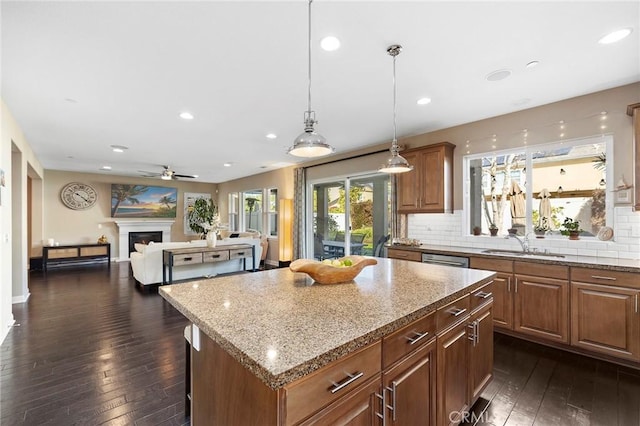 kitchen featuring brown cabinets, a kitchen island, a fireplace, and dark wood-type flooring