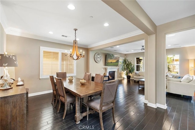 dining area with dark wood-style floors, visible vents, ornamental molding, a glass covered fireplace, and baseboards