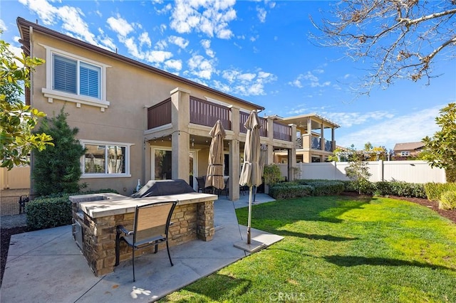 back of property featuring a patio, a balcony, outdoor dry bar, a yard, and stucco siding