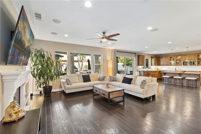 living area with a fireplace, visible vents, dark wood-style flooring, and recessed lighting