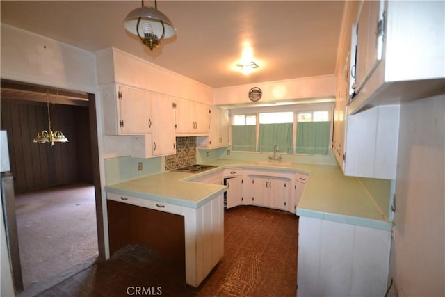 kitchen with white cabinets, black electric stovetop, light countertops, and decorative light fixtures