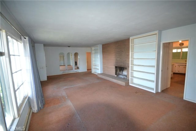 unfurnished living room featuring arched walkways, a large fireplace, and carpet flooring