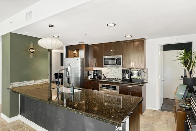 kitchen with a sink, dark brown cabinets, visible vents, decorative backsplash, and appliances with stainless steel finishes