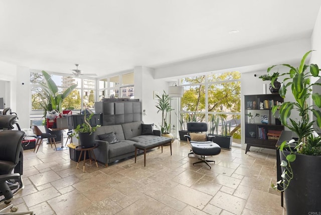 living room with a ceiling fan, a wealth of natural light, and stone tile floors