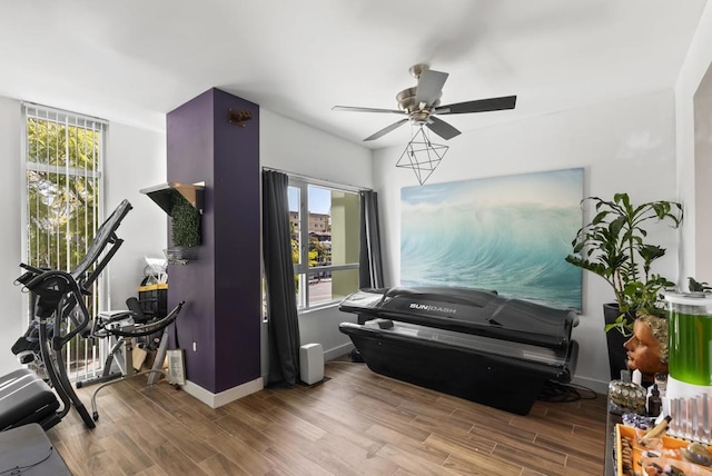 living area featuring baseboards, a ceiling fan, and wood finished floors