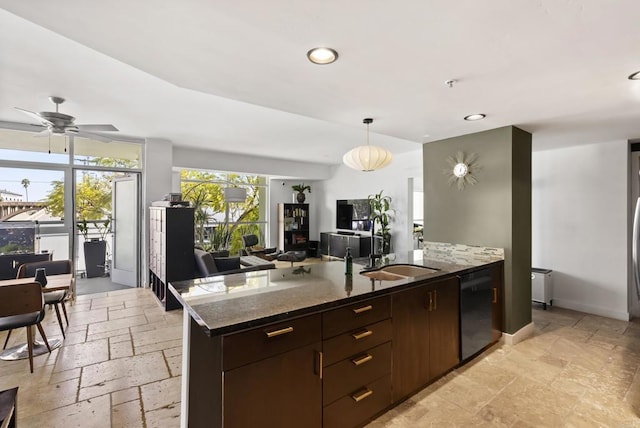 kitchen with a sink, stone tile floors, baseboards, a peninsula, and black dishwasher