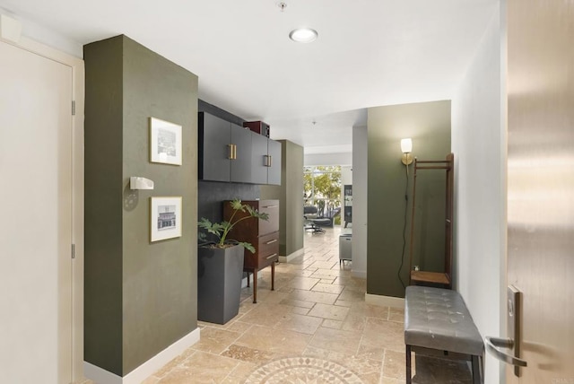 corridor featuring baseboards, stone tile flooring, and recessed lighting