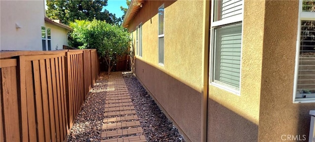 view of side of home featuring fence and stucco siding