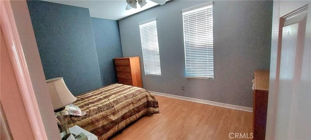 bedroom featuring multiple windows, baseboards, and wood finished floors