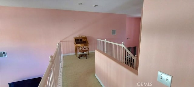 hall with light carpet, visible vents, baseboards, and an upstairs landing