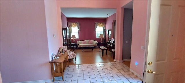 corridor with baseboards and light tile patterned floors