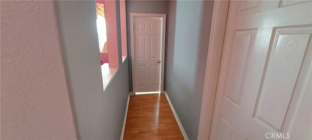 corridor with baseboards and wood finished floors