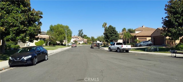 view of street with a residential view, curbs, sidewalks, and street lights